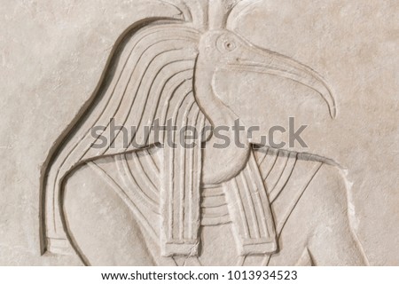 The Egyptian god Thoth with a bird's head on a stone bas-relief, background, texture Royalty-Free Stock Photo #1013934523