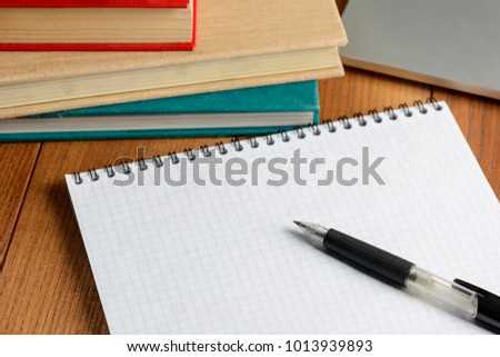 Ballpoint pen and notepad on a wooden table. Making notes while studying. Pupil's supplies.