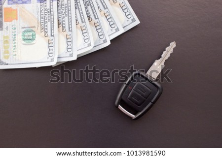 Car key on black background and money