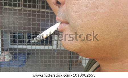 A close-up photo of a middle-aged man smoking tobacco and then out of his mouth smoke of white smoke. The concept of non-smoking campaign for people of all ages.