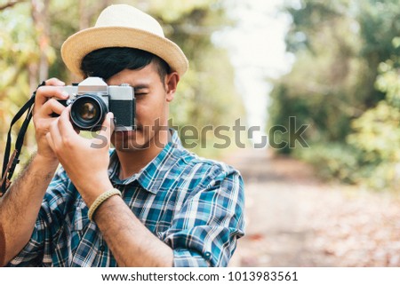 young hipster Asian man wearing plaid shirt holding the camera vintage 