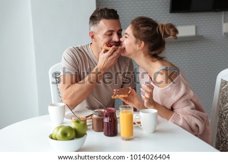 Portrait of a beautiful loving couple having breakfast while sitting at the table in a kitchen at home
