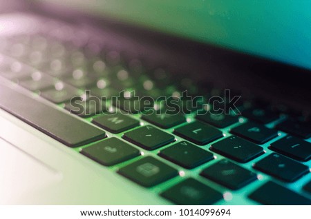 Close-up laptop keyboard with rainbow lighting, side view of laptop