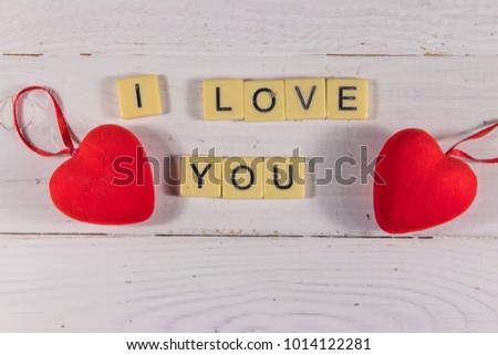 Red hearts and "I Love You" text on white wooden background. Top view
