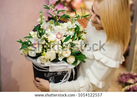 Happy and smiling blonde woman with a large and beautiful valentine box of white flowers
