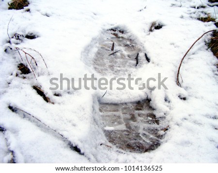 Human tracks in the snow. Forest trail in the field. Unknown pedestrians crossed the countryside. Winter time in nature. 