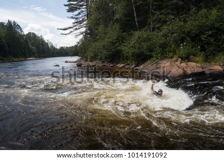 Canoeist stuck in a hole on the rapids of the Noire River, Quebec, Canada.