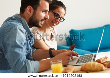 Husband and his wife sitting at the kitchen table.Breakfast.Using laptop for online shopping.
