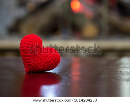 handmade red yarn heart on wooden table in the front Fireplace. the red heart on the left of picture and background copy space for text. Valentines day, love concept and love background