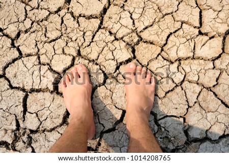 foot on dry cracked earth. Drought, the ground cracks, no hot water, lack of moisture. Dried and Cracked ground,Cracked surface,Dry soil in arid areas.