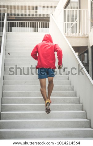 Back of sport man in red hood running up at steps, motion blur.