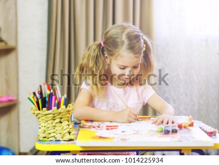 Little girl is painting with gouache. Happy little girl painting in at her home. Close up, selective focus.