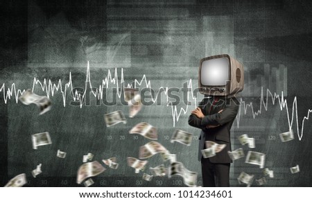 Businessman in suit with old TV instead of head keeping arms crossed while standing against flying dollars and analytical charts drawn on wall on background.