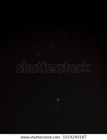 Orion's belt in the night sky along with the orion nebula in portrait frame