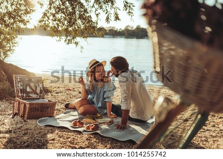 A young couple having a picnic at the beach Royalty-Free Stock Photo #1014255742