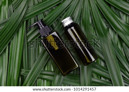 Cosmetic bottle containers on green herbal leaves background, Blank label for branding mock-up, Natural skincare beauty product concept.