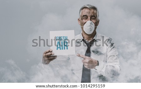 Confident man wearing a pollution mask and holding a fresh air sign Royalty-Free Stock Photo #1014295159