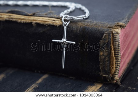 silver cross lies on the old holy bible