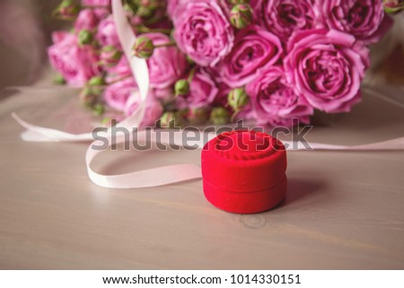 
velvet red box and a bouquet of pink roses lies on the table