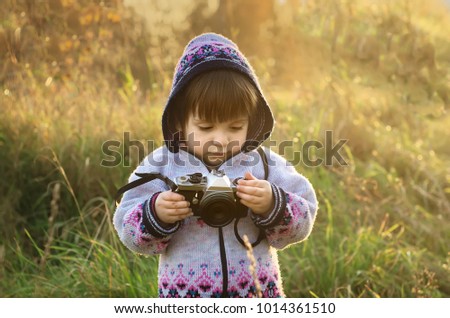 the child photographing the sunset in the meadow