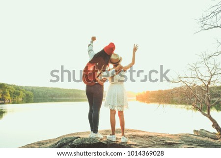 Two pretty girls backpack in nature, Raise your arms to convey success after reaching destination. Relax time on holiday and freedom life concept. Selective and soft focus, tone of hipster style.