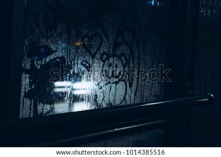 A sad drawing on the sweaty glass of a child's bear with hearts against the light of headlights