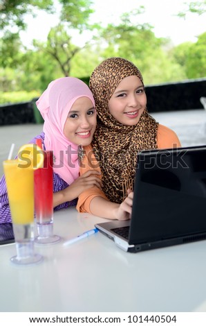 Two young pretty Asian muslim student in head scarf with laptop