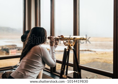 A woman looks into the distance through a telescope