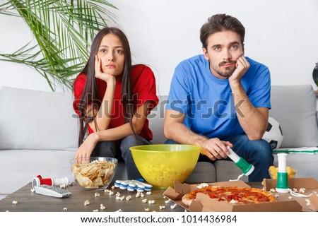 Young couple sport fans watching match boring game