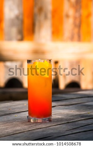 Colorful refreshing sunrise cocktail with orange juice and grenadine outside on a wooden old table Royalty-Free Stock Photo #1014508678