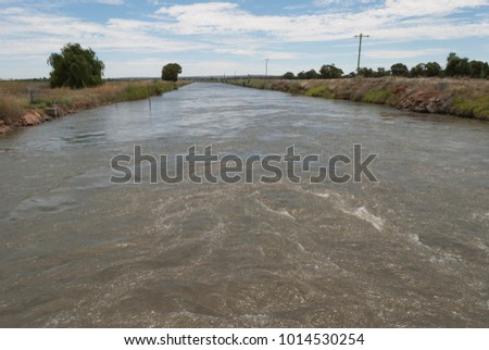 irrigation canal with flowing water for irrigation on a sunny day with clouds in the sky
