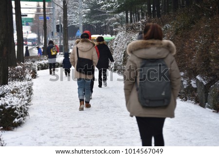 Pedestrians during a walk in melting snow covered pavement in Seoul, Korea.