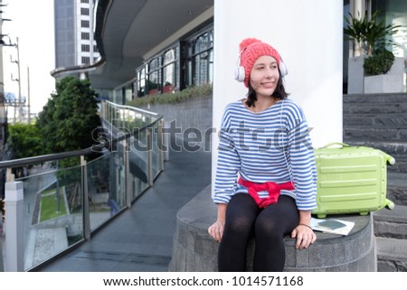 Young happy caucasian teenager listening to music while sitting in city, young traveler in headphones relax with music after walking all day, lifestyle recreation time in weekend concept