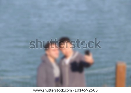 Blurred background of a couple taking selfie with the blue ocean behind them