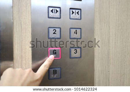Asian woman pressing the disabled elevator button with braille code of the elevator. Universal design. Soft focus. Technology, sign and symbol concept.
