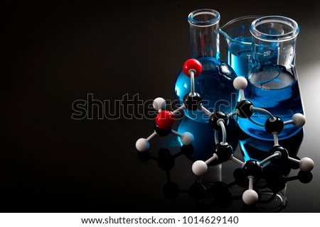 Organic chemistry, science class and STEM research concept with a methyl benzoate molecule on blue chemical solution in chemistry glassware, Erlenmeyer and Boiling (or Florence) flasks with copy space Royalty-Free Stock Photo #1014629140