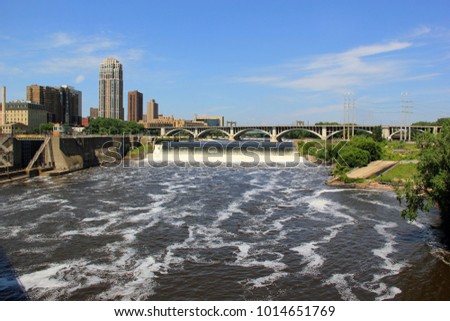 Summer sunny day in Minneapolis, Minnesota state, Midwest USA.Cityscape with downtown buildings and Third Avenue Bridge above Saint Anthony Falls and Mississippi river. Urban city architecture.