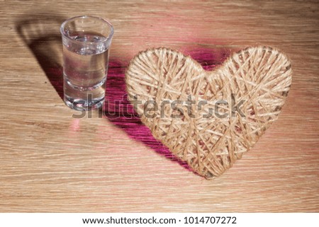 heart flax thread glass of vodka oak background