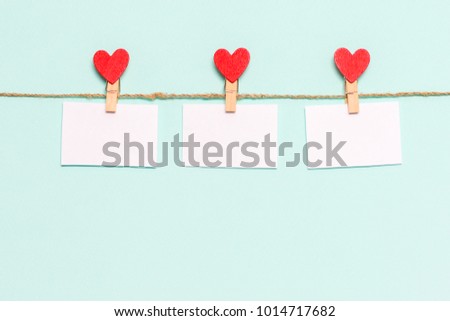 white pieces of paper pinned to rope with clothespins decorated with wooden hearts