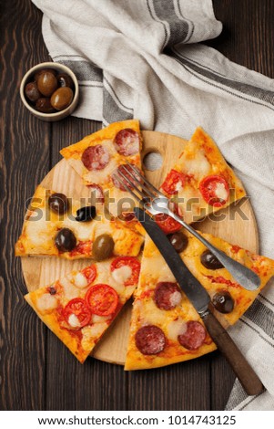 Pieces of different Greek pizzas with olives, Italian Margarita and Pepperoni on a dark wooden rustic background. Selective focus.  Top view. Copy space.
