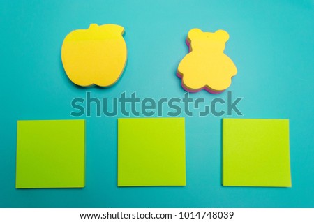 Empty yellow and green note paper, apple and teddy shape paper and Turquoise colour paper background. Empty blank for writing text and design. Top view with copy space, office desk