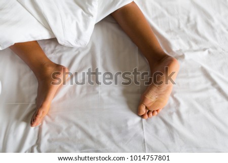 A girls feet amongst bedroom sheets. 