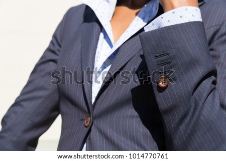 Business woman wearing a pin stripe suit - tailoring details on a dark skin / tanned model, showing cuffs, buttons, shirt