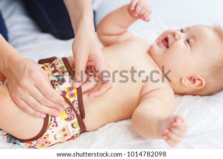 Woman's hands changing reusable diaper to baby. Eco concept