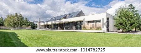 Modern construction of big luxurious home with grass and trees around Royalty-Free Stock Photo #1014782725