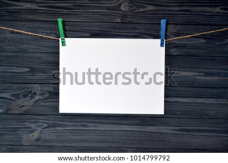 White sheet of paper fastened with a clothespin on a wooden wall.