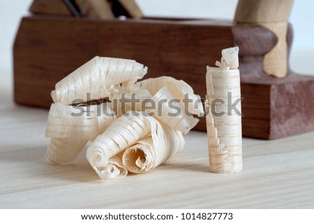 Shavings after planing of wood ash on the background of the plane close up.DIY concept. Woodworking and crafts tools. Carpentry hand tools. Wooden background.