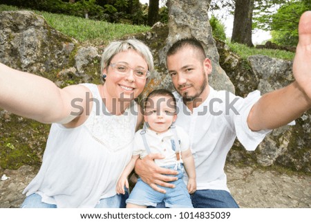 father and mother playing with their son make a selfie photo outdoor garden