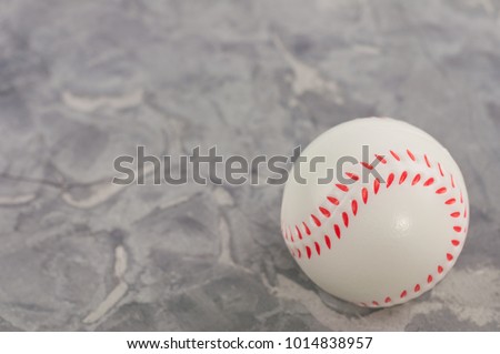 One new white and red soft rubber baseball ball on old worn cement