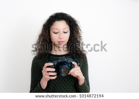 Young latin woman with a reflex camera with white background
